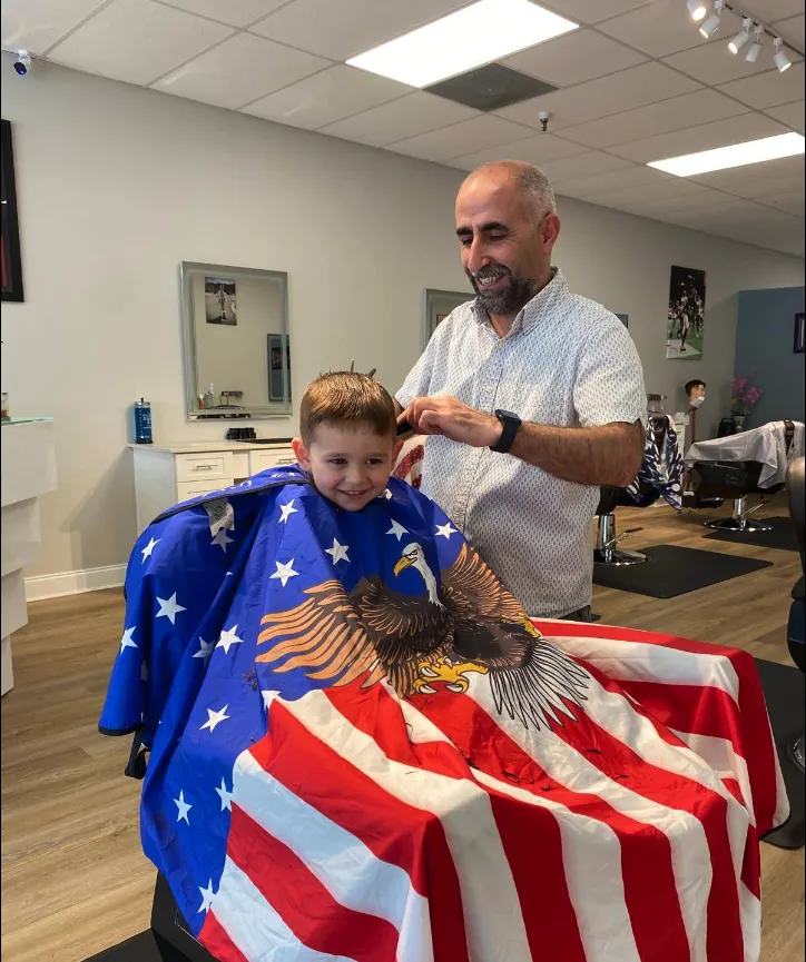 Hasim cutting a young customer's hair